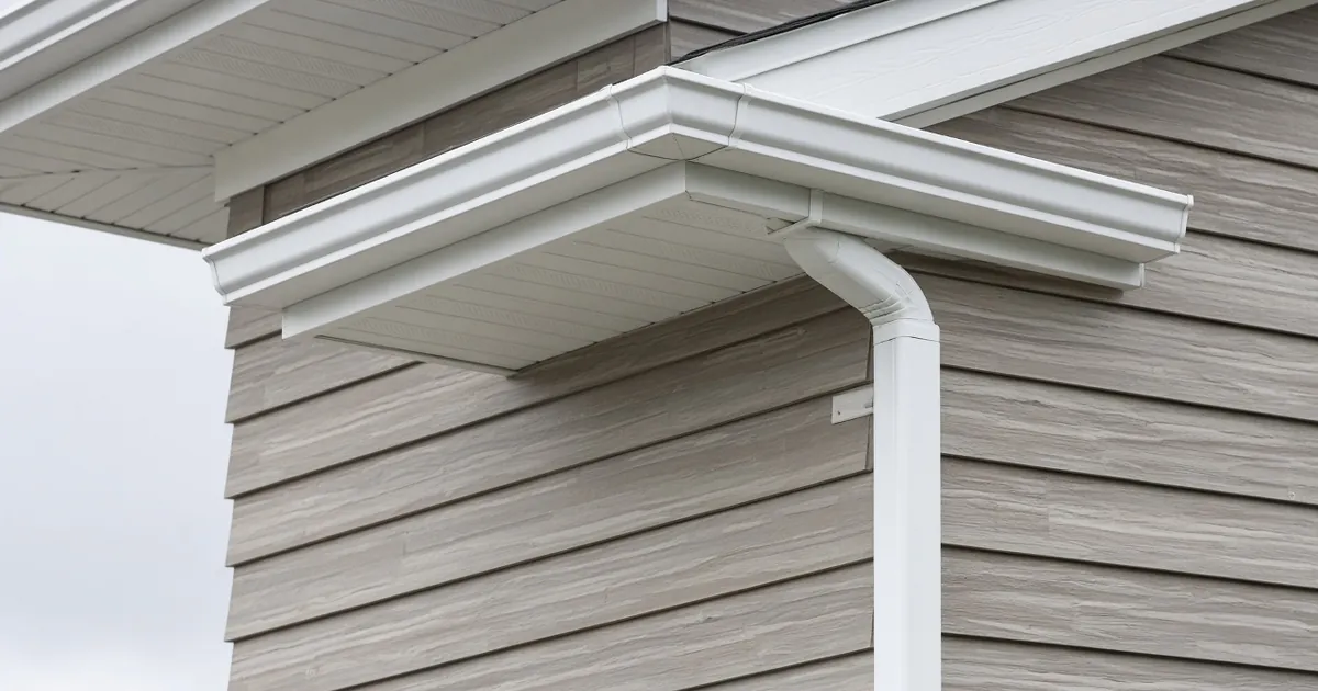 House eave with a clean aluminum gutter and downspout along the roofline